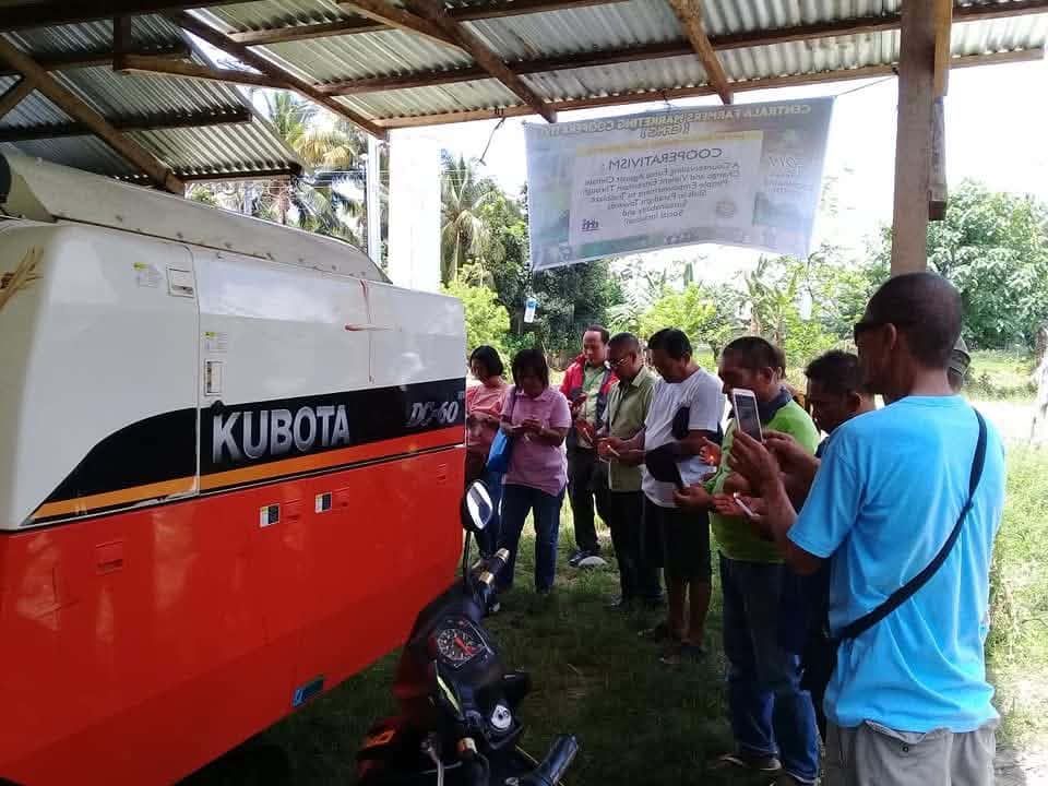 Cooperative members attending a seminar on cooperativism beside a Kubota combine harvester