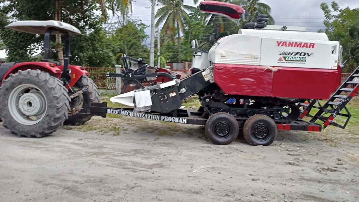 A new Yanmar AW70V combine harvester on a trailer pulled by a tractor, from the RCEF Mechanization Program